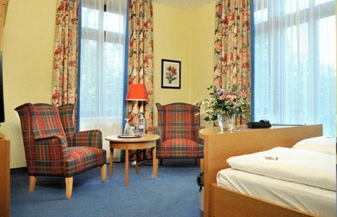 舍纳贝克浴疗公园酒店的酒店客房带两把椅子、一张桌子和一张床