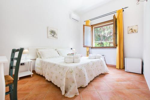 奇亚B&B La Vela Chia的白色的卧室设有床和窗户