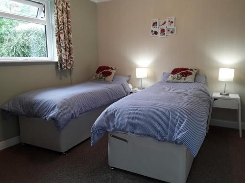 赫克瑟姆The Barn, Bellingham的一间卧室设有两张床、两盏灯和一个窗户。