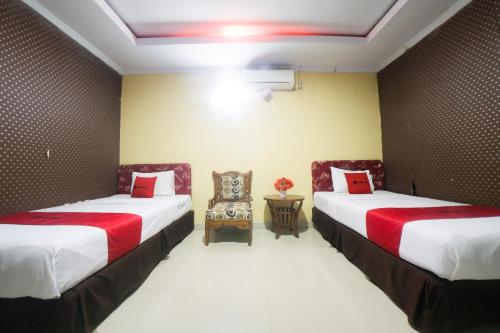 LimbotoRedDoorz Syariah near RSUD Ainun Habibie Gorontalo的一间设有两张床和椅子的房间