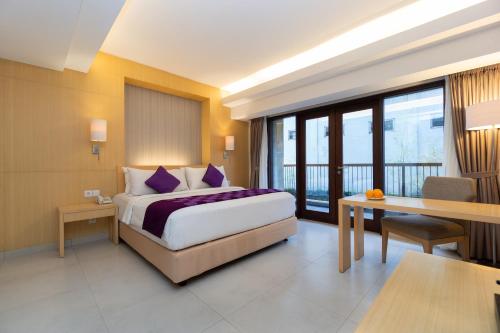 库塔Quest Hotel Kuta by ASTON的酒店客房配有一张床铺、一张桌子和一张书桌。