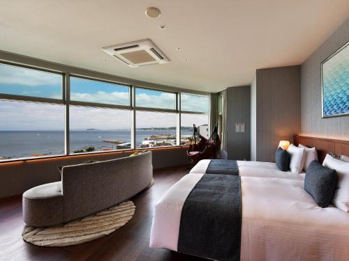 叶山町Hayama Umino Hotel的酒店客房带一张床、椅子和窗户