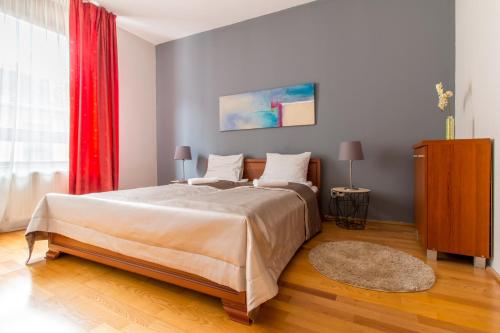 布达佩斯国王公寓酒店的一间卧室配有一张大床和红色窗帘