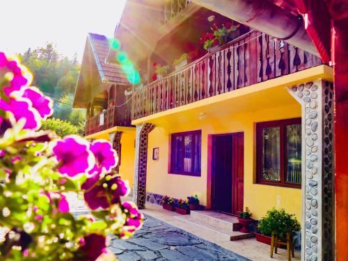 克尔茨什瓦拉乡Casa Ursu的黄色房子,设有阳台和鲜花