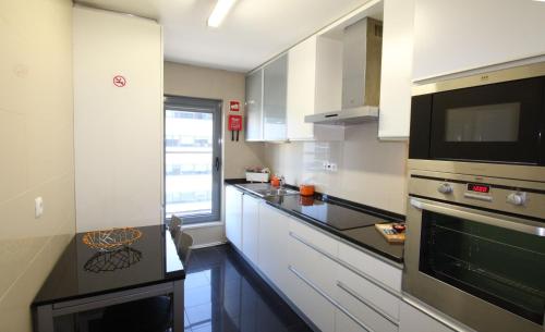 里斯本Parque das Nacoes River view ,free wifi的厨房配有白色橱柜和黑色台面