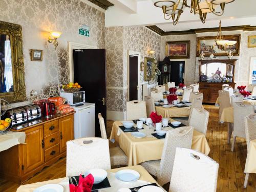 利物浦Castle Lodge Guest House 86-88 Sheil Rd L6 3AF的一间带桌椅的用餐室和一间厨房