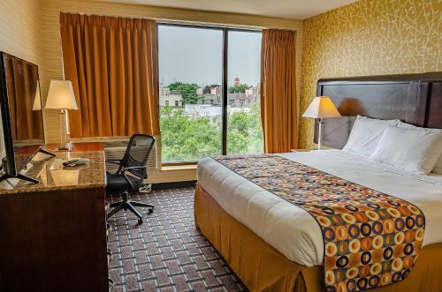 皇后区Elmhurst Hotel的配有一张床、一张书桌和一扇窗户的酒店客房