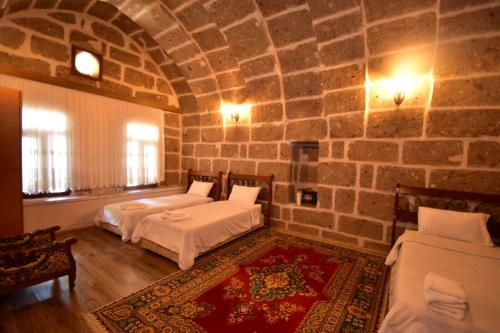 GuzelyurtKapadokya Ihlara Günalp Konağı的一间卧室设有两张床和石墙
