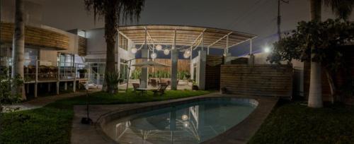 阿里卡Hotel Avenida en Arica的夜间在房子的院子中的一个游泳池