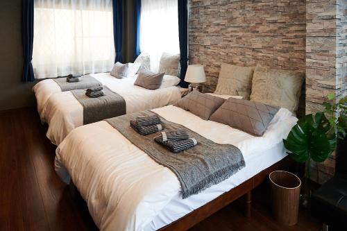 东京Ueno Residence Hotel Matsumoto的砖墙客房的两张床
