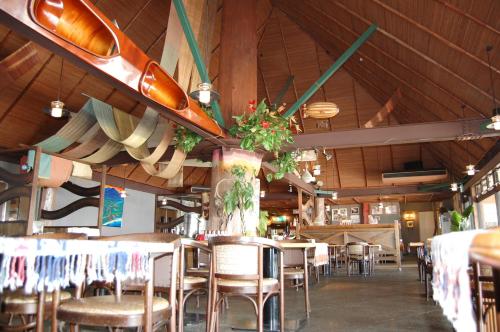 奄美奄美马车山村度假酒店的餐厅设有桌椅和冲浪板天花板