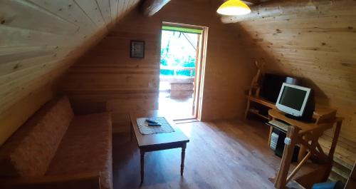 (( Čūskumuiža ))ŠMITI的小屋内的房间,配有桌子和电视