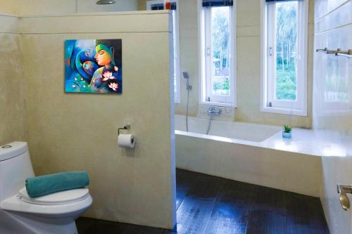 拉迈棕榈景观别墅的一间带卫生间和浴缸的浴室以及一幅画