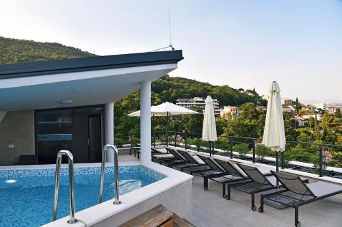 奥帕提亚Apartments in Villa Ziza, rooftop swimming pool的一座大楼内的游泳池,配有椅子和遮阳伞