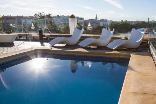 塞维利亚里贝拉特里亚纳酒店的一组坐在游泳池旁的白色椅子
