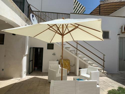 圣凯撒利亚温泉Villa Azzurra Sct的一把大伞,坐在椅子和楼梯旁