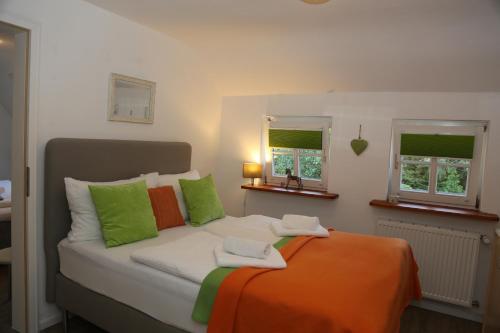 萨巴赫瓦登Hotel-Berggasthof Schwarzwaldperle的一张带绿色和橙色枕头的床以及两个窗户
