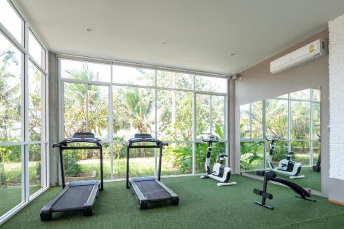 拉差汶里Navela Hotel & Convention的一个带跑步机和椭圆机的健身房,位于带窗户的房间内
