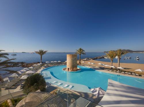 普拉亚登博萨Hotel Torre del Mar - Ibiza的一个带遮阳伞的游泳池和一个海滩