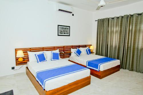 阿努拉德普勒Sapumal Lodge的一间卧室配有两张带蓝色枕头的床