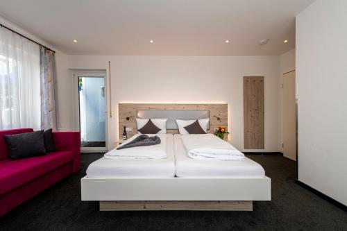 康斯坦茨霍尔泽旅舍的卧室配有一张白色大床和一张红色沙发