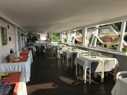 萨巴赫瓦登Hotel-Berggasthof Schwarzwaldperle的餐厅设有白色的桌子和白色的椅子及窗户。