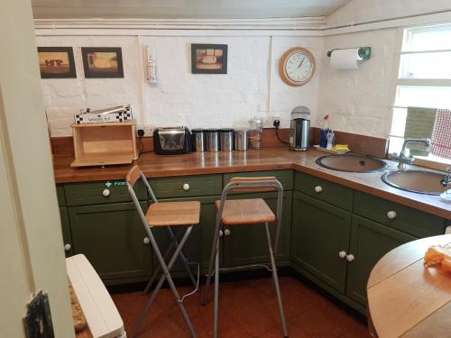 圣奥尔本斯KEYFIELD TERRACE SERVICED APARTMENTS的厨房配有绿色橱柜和带2张凳子的台面