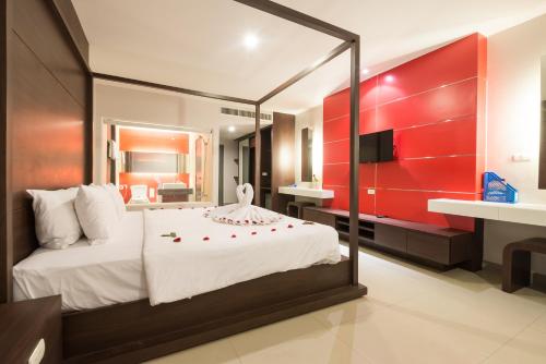 芭东海滩Alfresco Phuket Hotel的一间卧室设有一张红色墙壁的大床