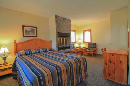 Otter Lake阳光角度假村有限公司的一间卧室设有一张大床和一个壁炉