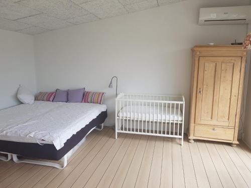 Allingåbro1 room with private Bath的一间卧室配有一张床、一张婴儿床和橱柜。