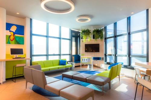 巴格那提卡贝加莫机场酒店的客厅设有黄色和绿色家具和窗户。