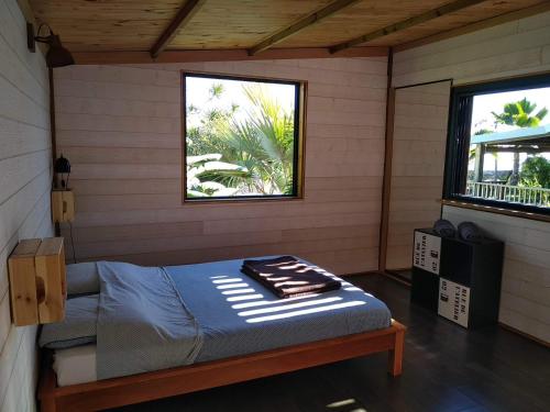 BellemèneBungalow cosy avec piscine surplombant l'océan的卧室配有床,位于带2个窗户的房间