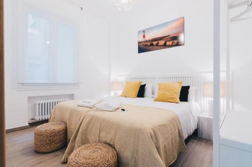 毕尔巴鄂Amalur apartment by People Rentals的白色卧室配有两张带黄色枕头的床