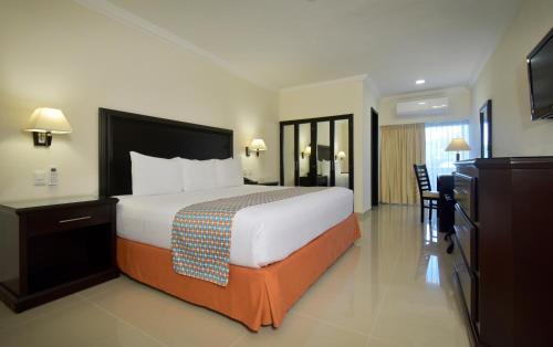 坎昆Hotel Bonampak的酒店客房设有一张大床和一台电视。