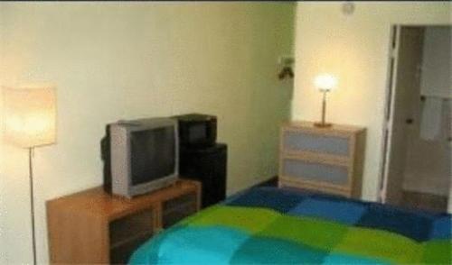 红木城红木城西阔尔宾馆的一间卧室配有一张床和一张桌子上的电视