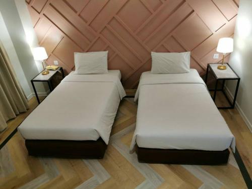 乌汶丽晶乌汶酒店 的配有两盏灯的小房间内的两张床