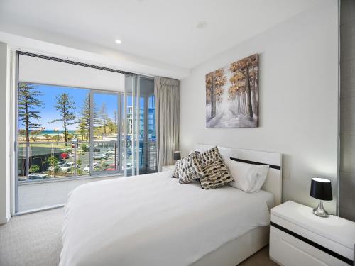 黄金海岸尼瓦纳海滨公寓的卧室设有白色的床和大窗户