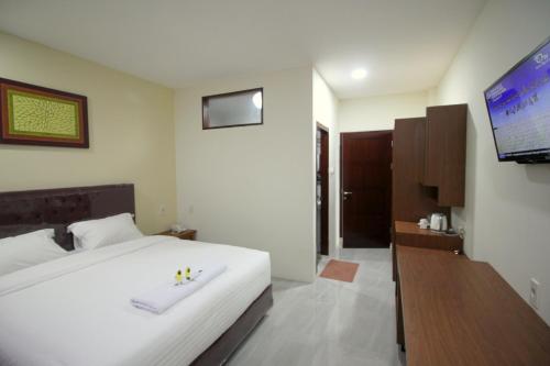 班达亚齐Grand Mahoni Hotel的卧室配有白色的床和平面电视。