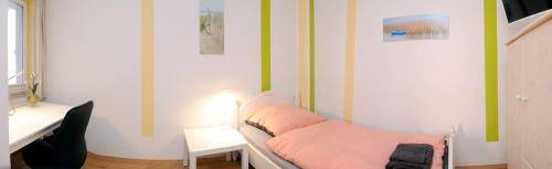 新明斯特FineApartment Neumünster的客房配有带粉红色床单的床和书桌。