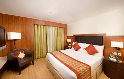 新德里Svelte Hotel and Personal Suites的酒店客房带一张大床和一把椅子