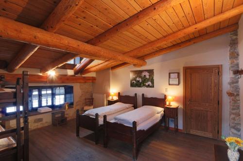 阿切廖Albergo Locanda Mistral的一间卧室设有两张床和木制天花板