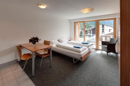 采尔马特Good Value Apartments by Mountain Exposure的客房设有床、桌子和窗户。