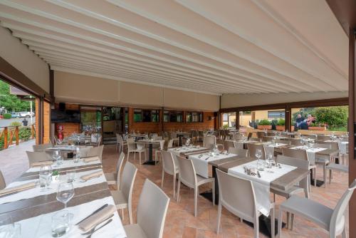 圣皮耶罗阿谢韦木吉罗维尔德营地村酒店的餐厅设有白色的桌椅和窗户。