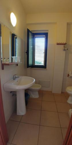 罗萨诺La Piana degli Ulivi的一间带水槽和卫生间的浴室以及窗户。