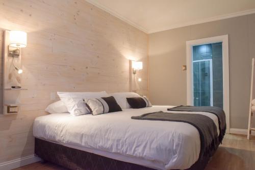 蓬塔阿雷纳斯Hostal Boutique Puerta Roja的卧室配有一张白色大床和木墙