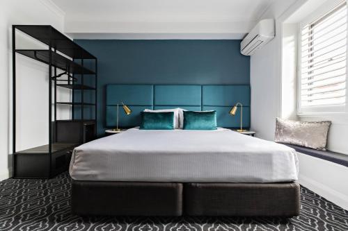 悉尼Avoca Randwick by Sydney Lodges的一间卧室配有一张带蓝色墙壁的大床