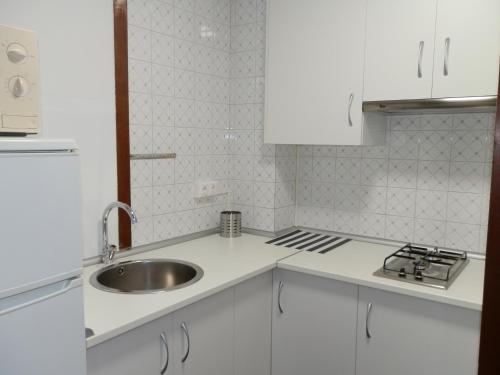 佩里洛Apartamentos Turisticos Beatriz的白色的厨房设有水槽和炉灶。