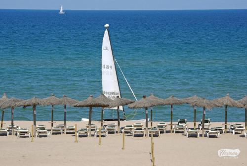 帕尔斯海滩高尔夫度假公寓的海滩上的帆船,配有椅子和遮阳伞