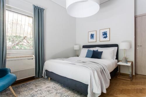 雅典Bright 2BD Apartment in Psychiko by UPSTREET的一间卧室配有一张大床和一张蓝色椅子