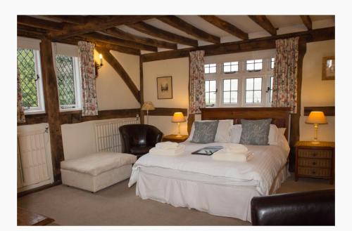 温莎The Old Farmhouse的一间卧室配有一张床、一把椅子和窗户。